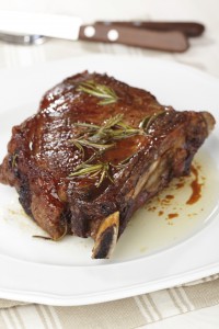 Roasted rib steak with rosemary on white plate